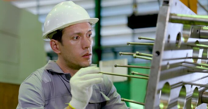 Asian male technician checks guide rod position on metal fixture, reviewing hole alignment, component detail, safety condition, precision setup, maintenance workflow in , slow motion.