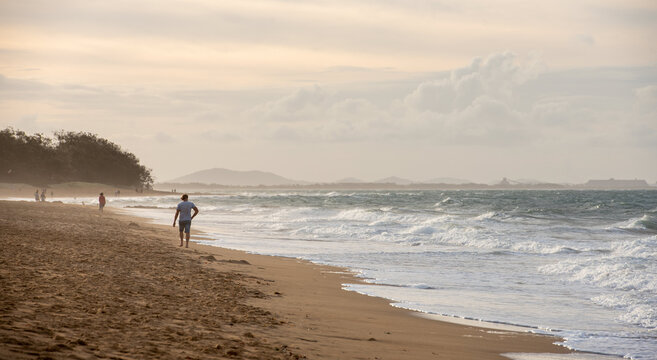 Beach walker at sunset with misty hills