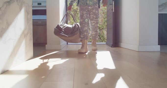 After duty male soldier entering open door holding duffel placing bag on floor standing in sunlight