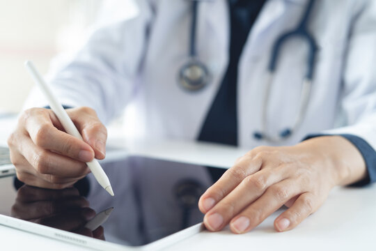 Close up of doctor using stylus epn on digital tablet, working at medical clinic office. 