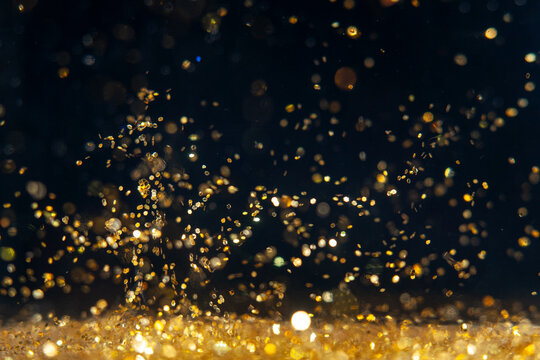 Swirling golden particles dance in darkness creating a vibrant visual display