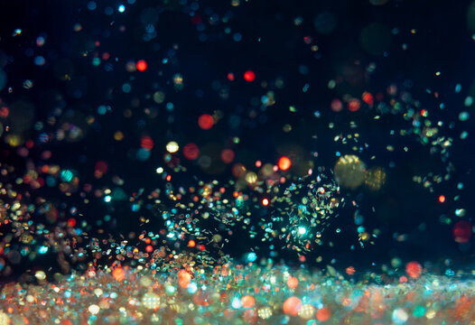 Colorful particles shine in dark background with soft light at night