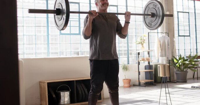 Trainer cueing, male lifter bending, gripping barbell on platform, pressing up for strength in loft