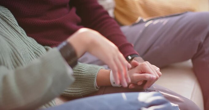 Couple on couch, woman checking white smartwatch, tapping, counting, man with hands clasped