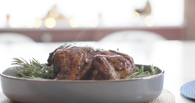 Camera is pulling back, revealing glazed roast on oval dish by window as steam is rising