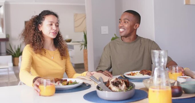 Couple sitting at table, woman seeing turkey pan reaching both clinking juice glasses starting meal