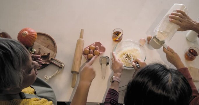 Diverse women starting batter prep for baking, sifting flour, whisking and passing cups at island