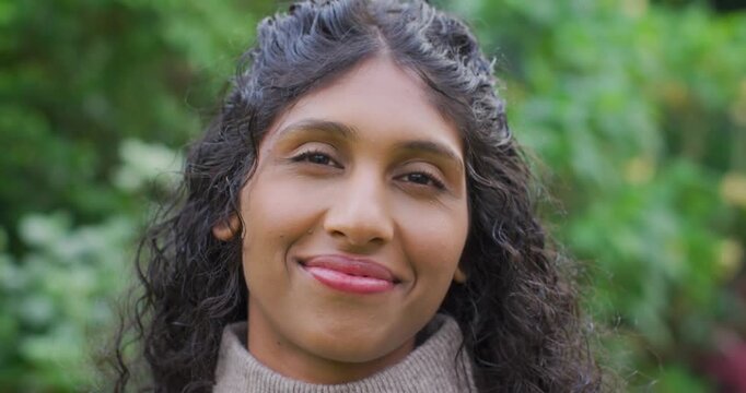 African American woman holding smile, relaxing and laughing, looking at camera, wearing tan sweater