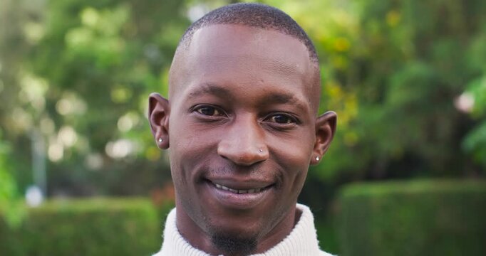 African-American man reacting to cam opening eyes meeting cam smiling laughing in garden nose-stud