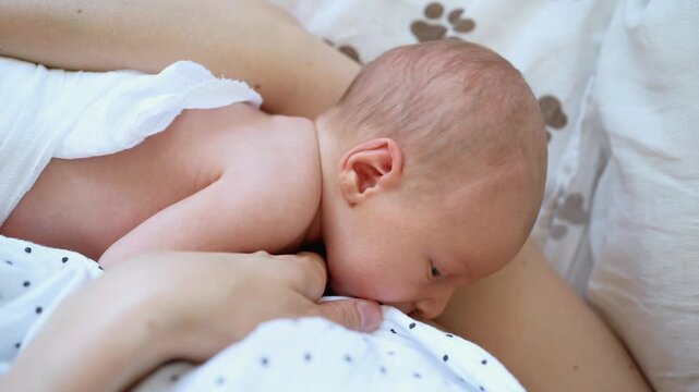 Newborn baby boy sleeping calmly on his mother's chest after breastfeeding. Embodying a gentle moment of maternal love and affection. The close up view highlights the intimate bond and nurturing care
