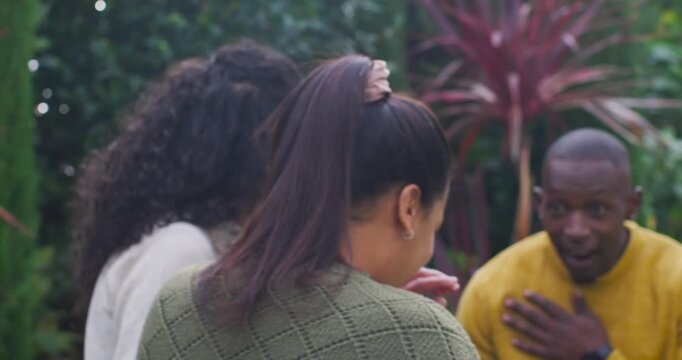 Garden friends curly woman playfully tugging scrunchie, woman sipping glass, man in yellow laughing