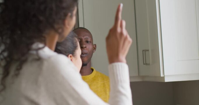 Friends seeing African American man reacting after spoon jab then fist bumping near bowl on counter
