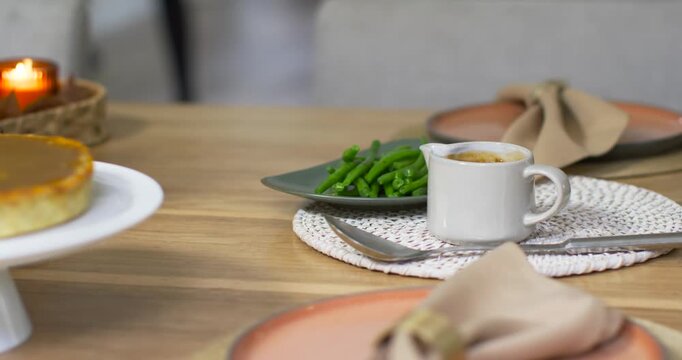 Camera is starting slow pass across wooden dining table, highlighting espresso cup and green beans