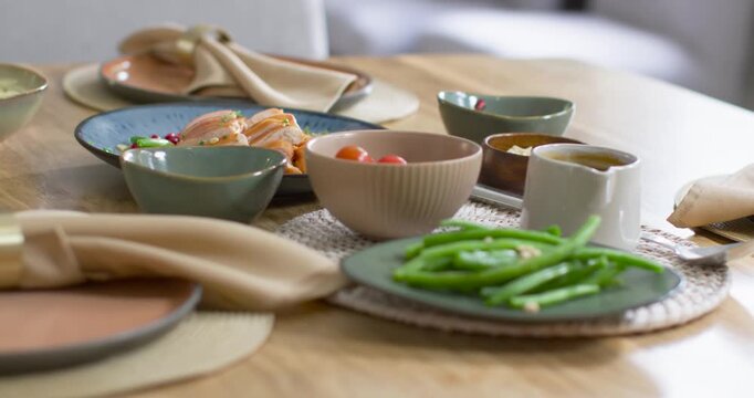 Camera is closing in and focusing on green beans at dining table, highlighting texture and garnish