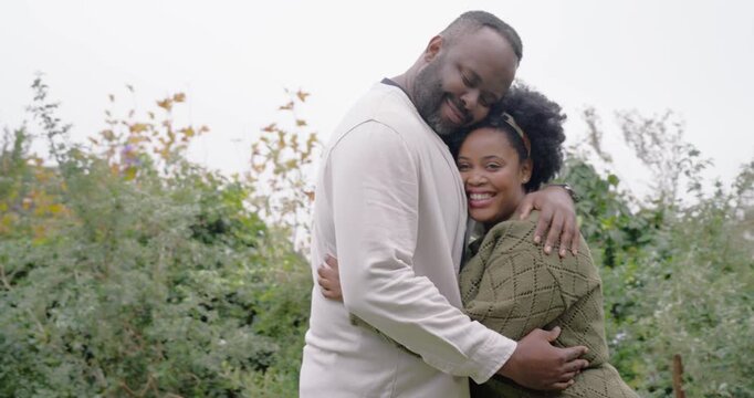 African couple locking eyes, reaching hands, hugging in garden, reuniting, watch, headband, stake