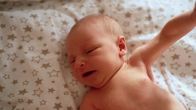 Close up of crying newborn infant lying in a crib at home, expressing discomfort, sadness, and hunger through whimpering, tears, and wriggling, highlighting early infancy challenges