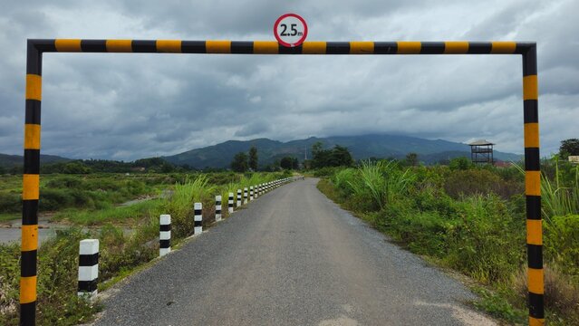Rural Road with Height Restriction Barrier, Entrance Gate in Countryside Landscape. Height limit barrier with 2.5m sign on a rural asphalt road.