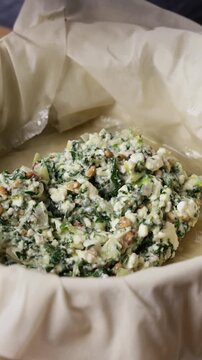 Adding Greek Spinach Feta Pie Filling To Phyllo Dough Pan Front View Vertical