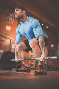 Determined man with tattoos deadlifting at the gym
