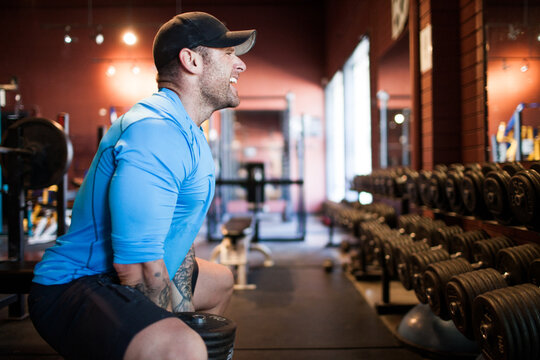 Side view of muscular man lifting heavy dumbbell