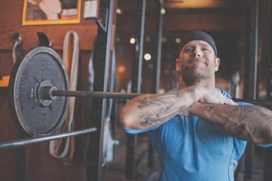 Tattooed man preparing for front squats at the gym