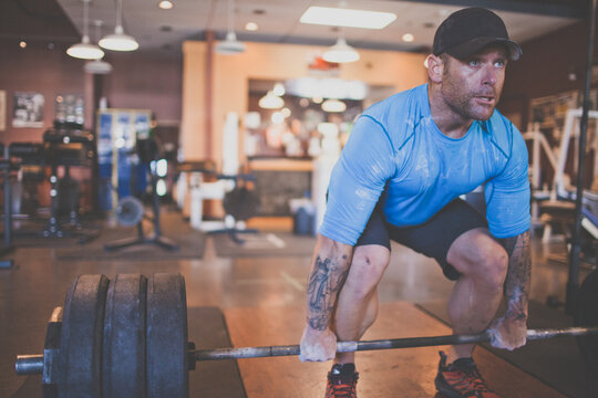 Strong tattooed man preparing for deadlift at the gym.