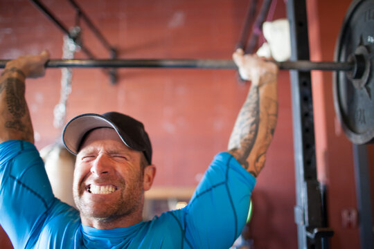 Determined man straining to lift a heavy barbell overhead