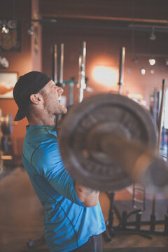 Man strength training, grimacing while lifting heavy weights