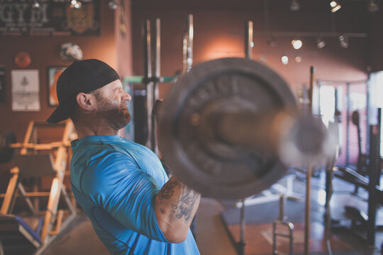 Bearded man with tattoos doing bicep curls at gym