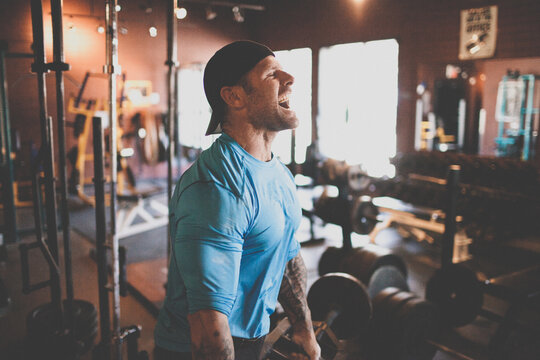 Muscular man roaring during intense gym workout