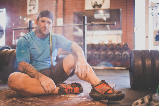 Weightlifter sitting on floor covered in chalk dust
