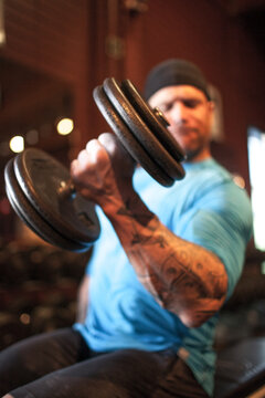 Muscular man with tattoos doing bicep curls