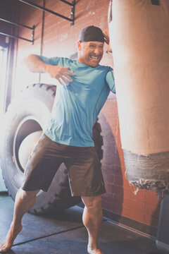 Fit man laughing while hitting a heavy bag