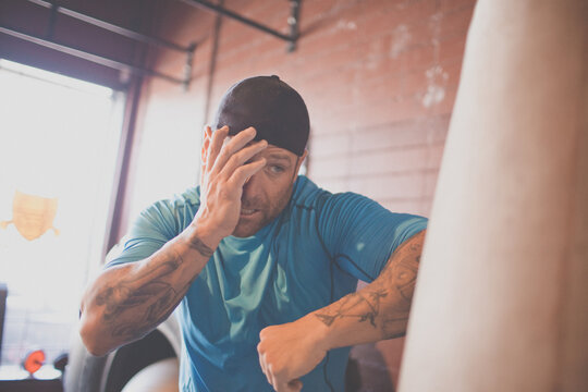 Tired tattooed man takes a break from boxing training