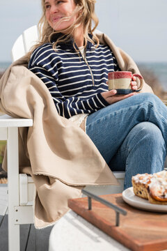 Woman enjoying coffee on a sunny seaside deck