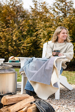 Woman relaxing outside in chair with blanket