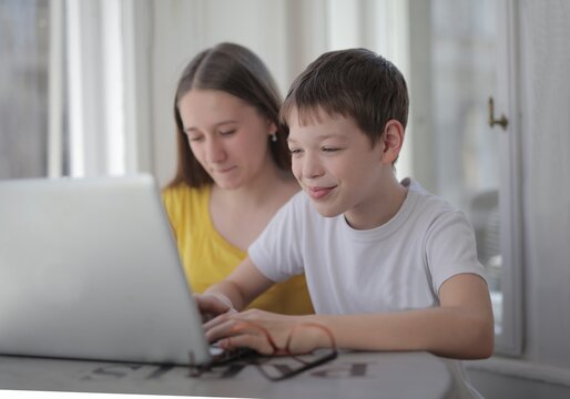 Smiling young boy and sister using a laptop together