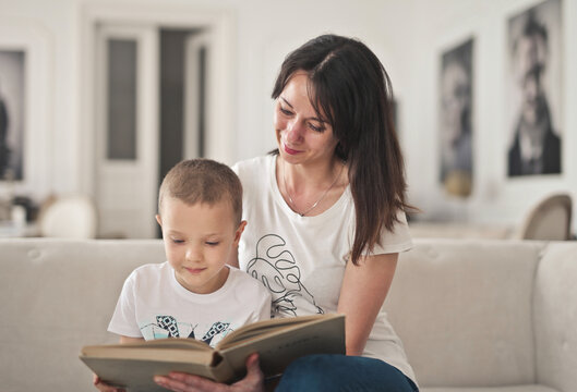 Smiling mother reads a book with her young son