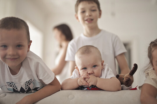 Cute baby and his older siblings posing on a couch