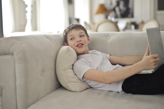 Young boy relaxing on a couch using laptop computer