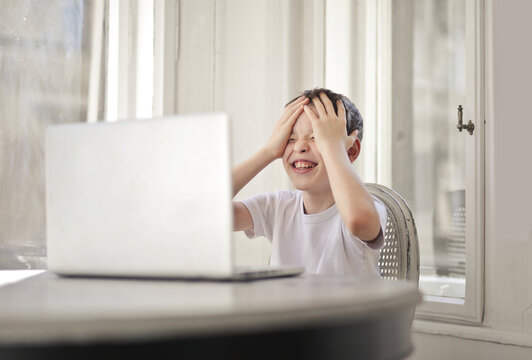 Young boy frustrated with his laptop computer