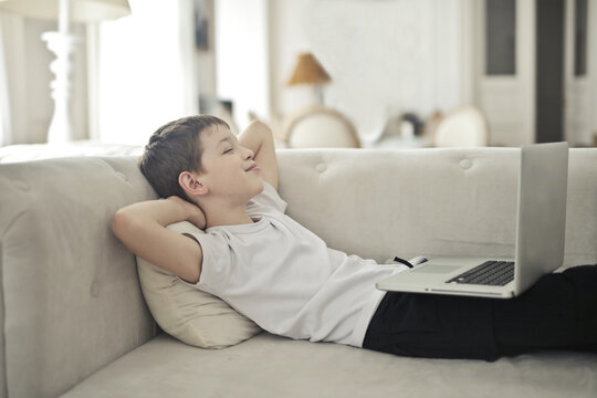 Content boy relaxing on sofa with a laptop