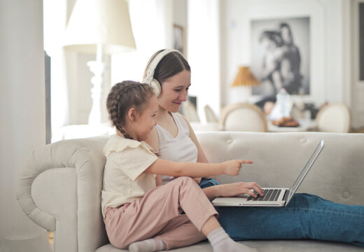 Little sister points at laptop with older sister