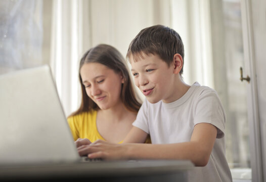 Brother and sister happily using a laptop together