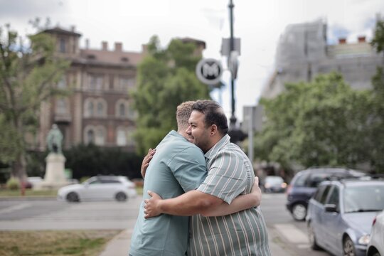 Two male friends embracing on a city street