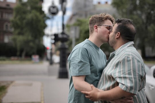 Loving male couple kisses on a sidewalk