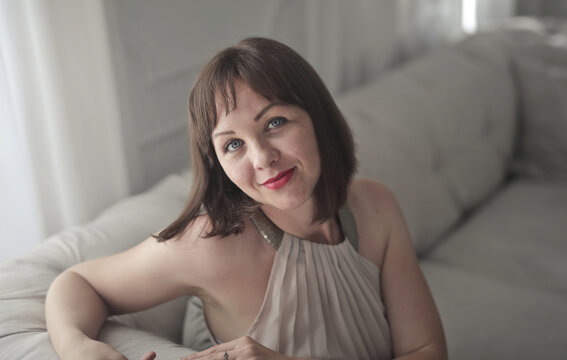 Confident brunette woman with blue eyes smiling at home