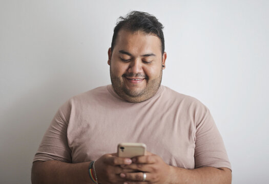 Happy plus size man smiling at his smartphone
