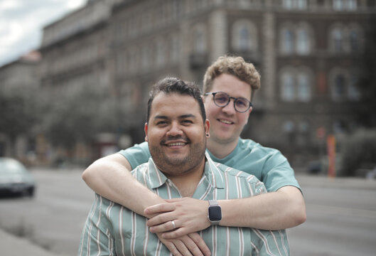 Happy male couple hugging on a city street