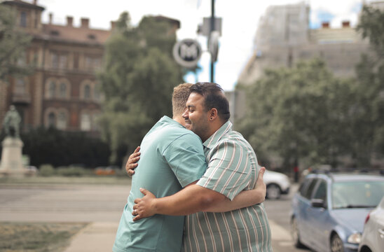 Two male friends sharing a warm hug on a city street